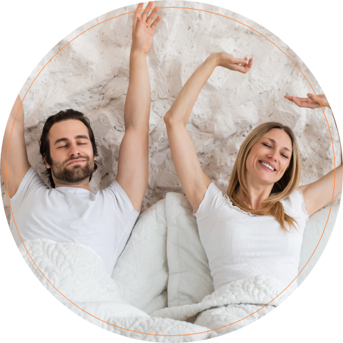 Smiling man and woman stretching in bed after sleep apnea treatment in Mesa Arizona