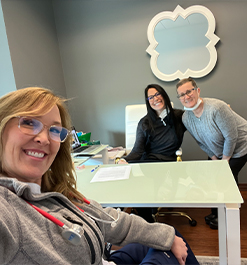 Selfie of Doctor Layman and two team members across desk