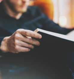 Person sitting in armchair reading book with plain black cover