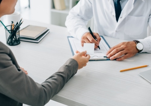 Person handing payment card to their doctor across a desk