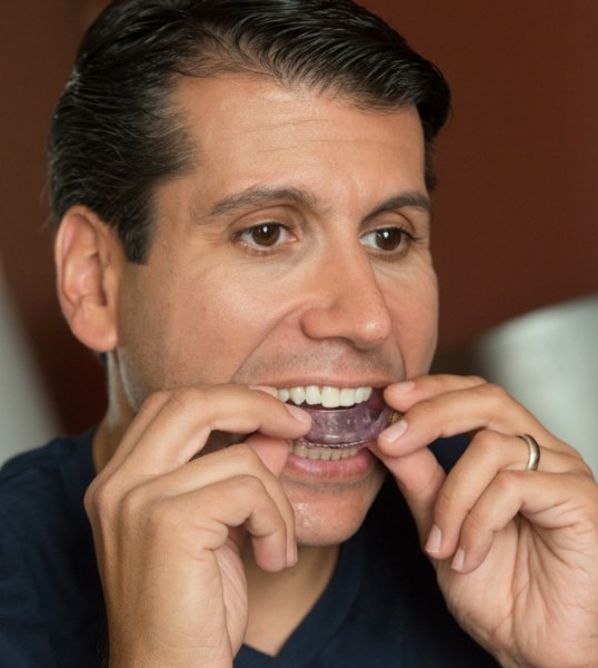 Man placing light purple oral appliance into his mouth