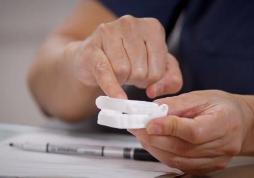 Person pointing to a set of white oral appliances with their pinky finger