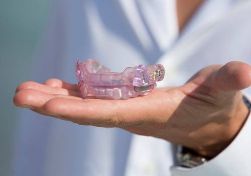 Person holding set of light purple oral appliances in their hand