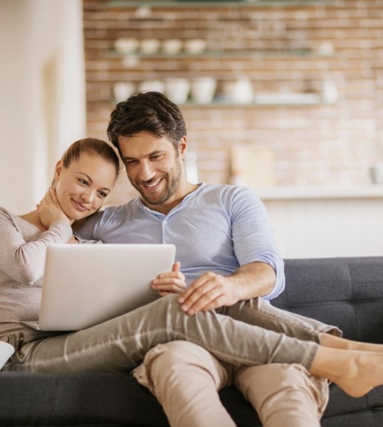 Man and woman cuddling on couch reading sleep apnea doctor reviews on laptop