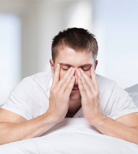Man in bed rubbing eyes and needing sleep apnea treatment in Mesa