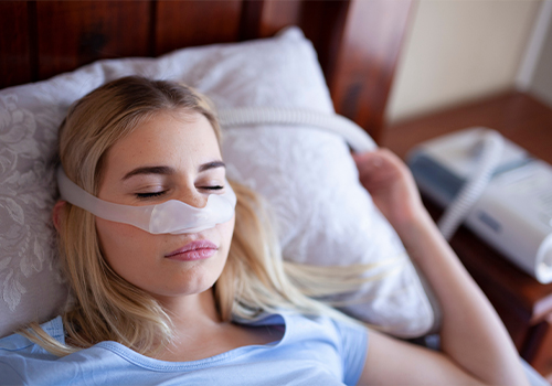 Young woman sleeping while wearing a C P A P mask on her face