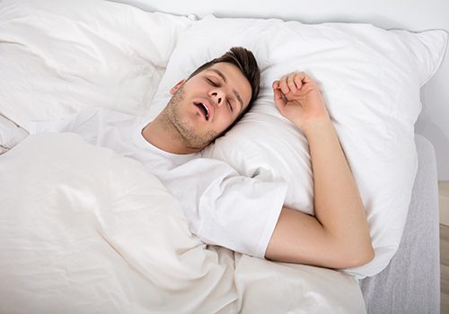 Snoring man lying on his back in bed