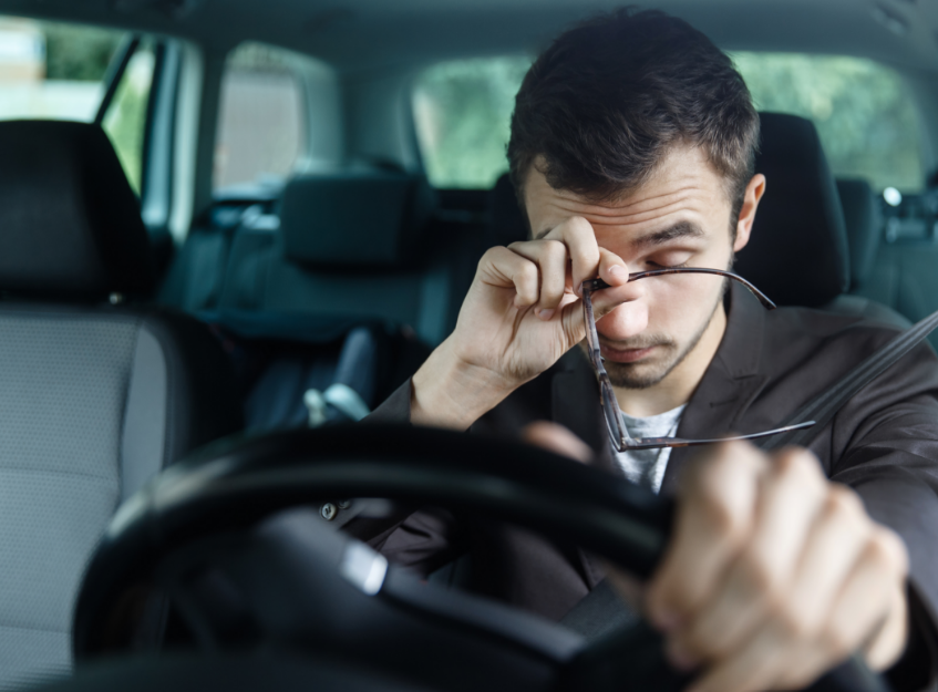 Tired man driving and rubbing his eye